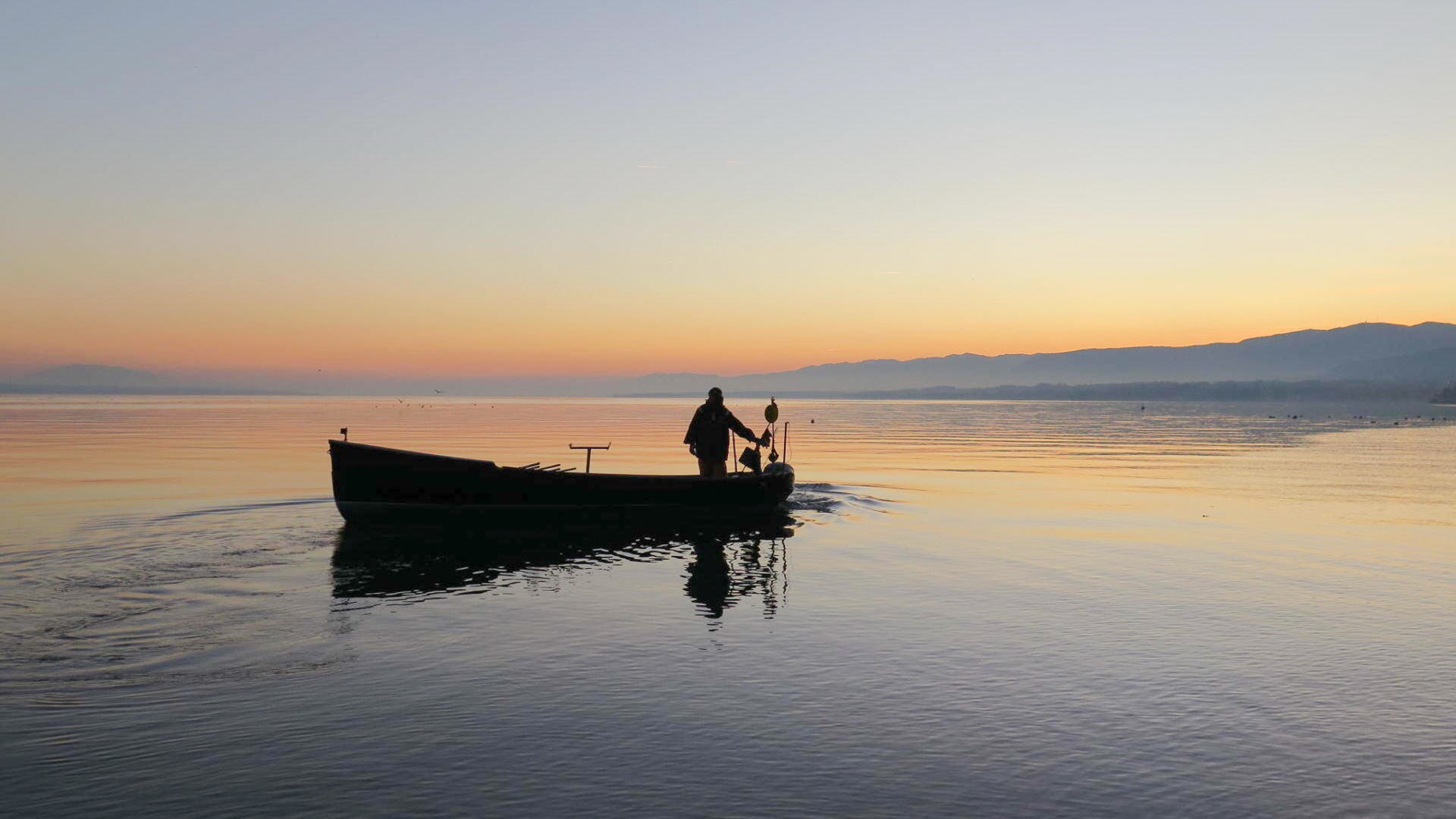Pêcheur sur le lac de Neuchâtel au coucher du soleil